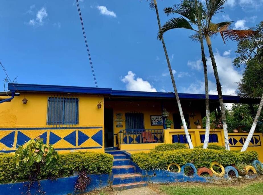 una casa amarilla con palmeras delante en Finca Hotel Alto la María, en Angelópolis