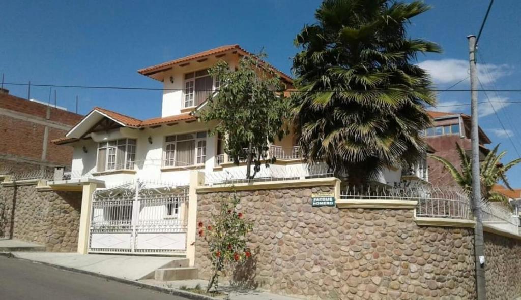 a white house with a stone wall and a tree at Casa con Piscina en Cochabamba in Cochabamba