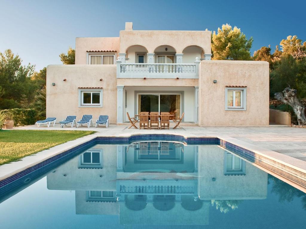 una casa con piscina frente a ella en Belvilla by OYO Can Cova, en Sant Josep