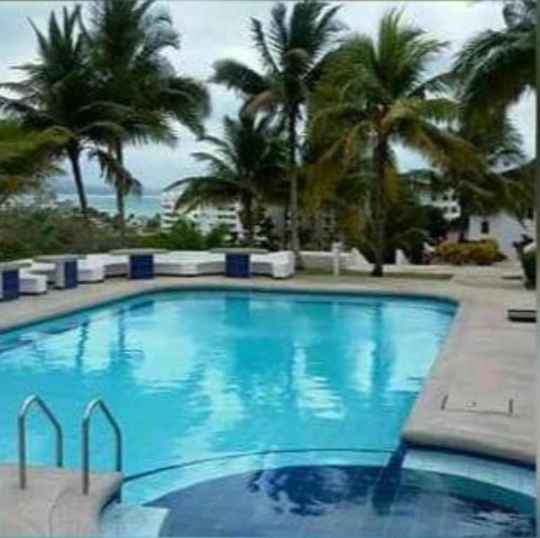 una gran piscina azul con palmeras y el océano en Casa completa SAME Casa Blanca, en Same