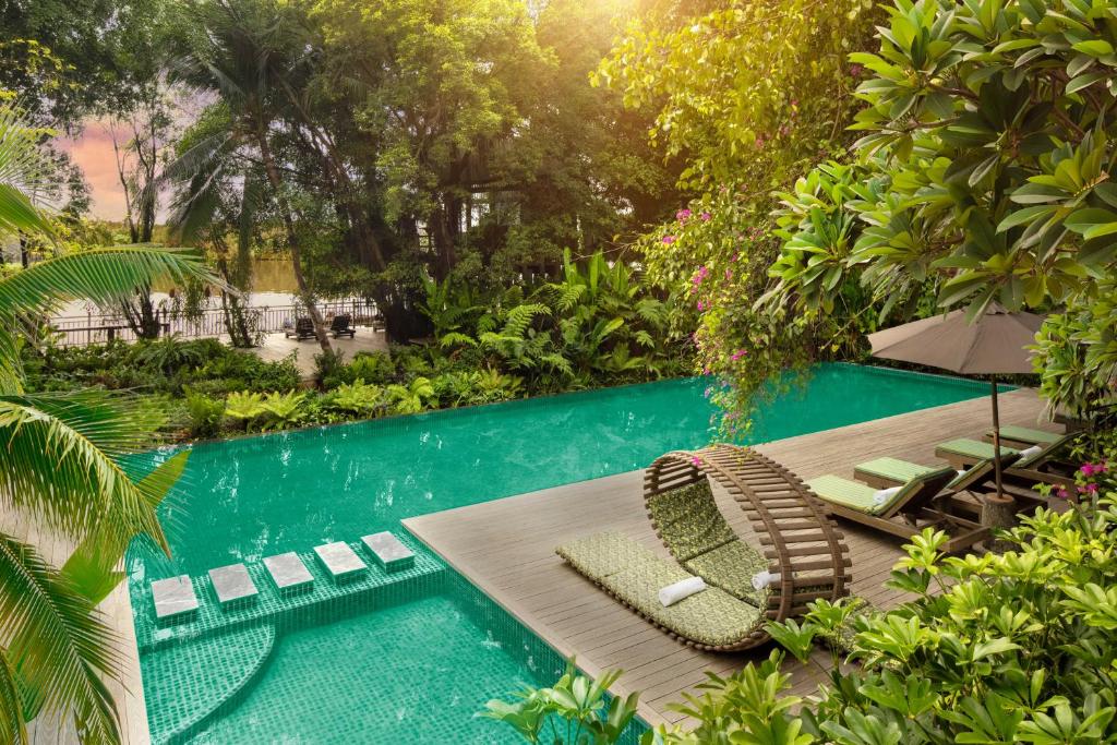 una piscina con mesa y sillas junto a una piscina en An Lam Retreats Saigon River, en Ho Chi Minh