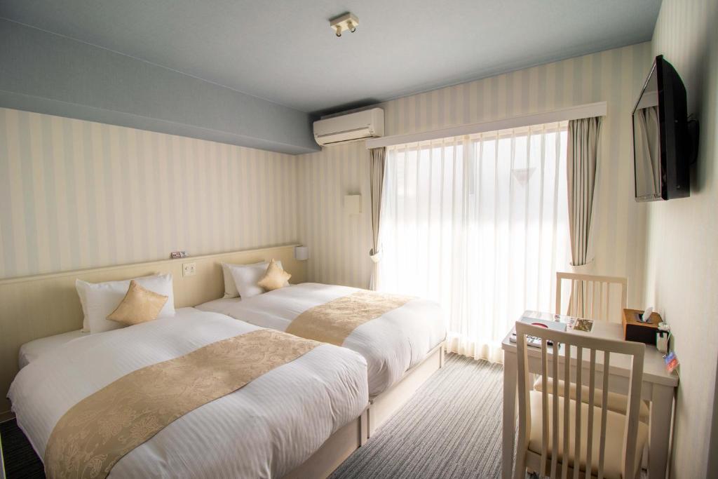 京都市にあるフランボワーズ 京都 ホテル・ドゥ・シャルムのベッド2台と窓が備わるホテルルームです。
