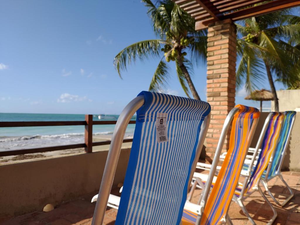 2 sillas sentadas en un balcón con vistas a la playa en Casa completa pé na areia en Maragogi