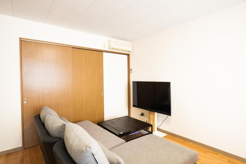 a living room with a couch and a flat screen tv at STAY IN PASSION in Asahikawa