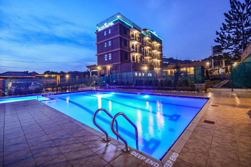 Una piscina frente a un edificio por la noche. en Mlex Hotel, en Kampala