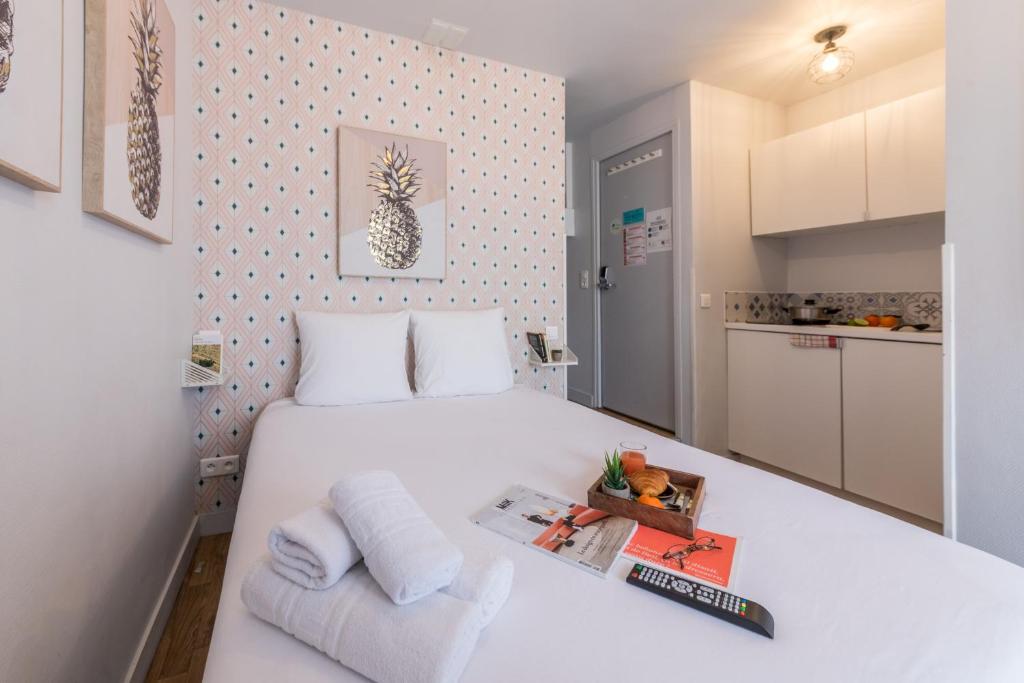 niewielka sypialnia z białym łóżkiem i kuchnią w obiekcie Apartments WS Opéra - Galeries Lafayette w Paryżu