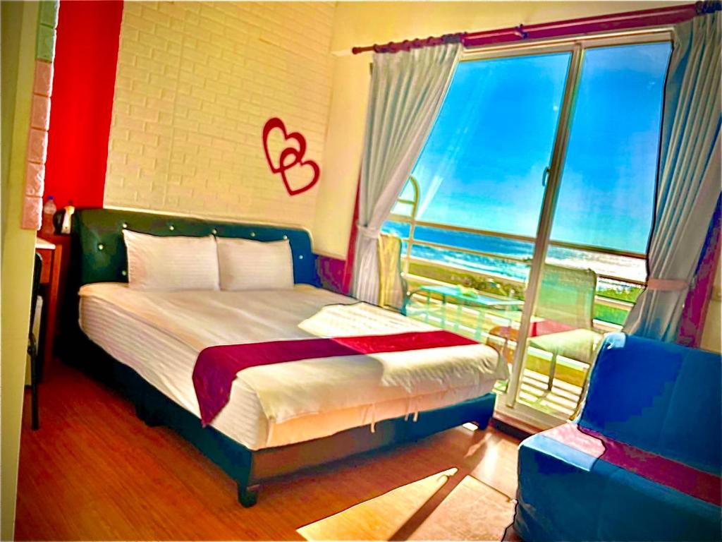 a bedroom with a bed and a large window at Fei Li Jin Hotel in Kenting