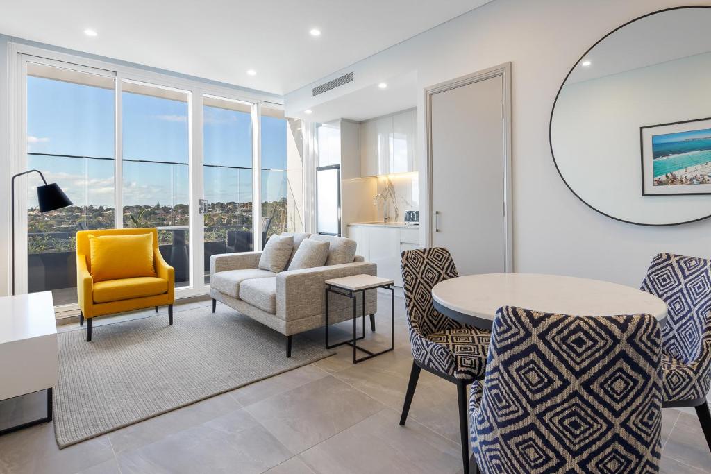 a living room with a couch and a table and chairs at Meriton Suites Bondi Junction in Sydney
