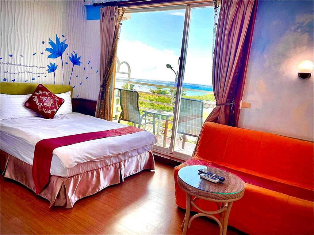 a bedroom with a bed and a chair and a window at Fei Li Jin Hotel in Kenting