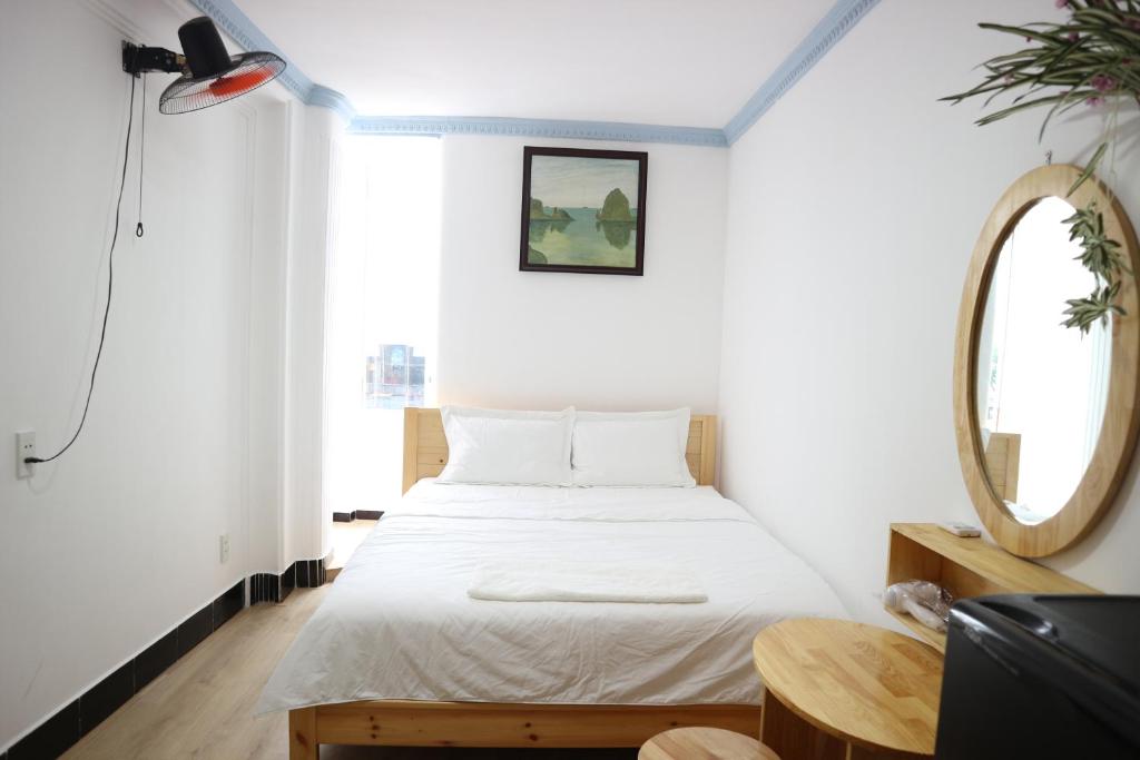 um quarto com uma cama branca e um espelho em Loan Võ hostel em Cidade de Ho Chi Minh