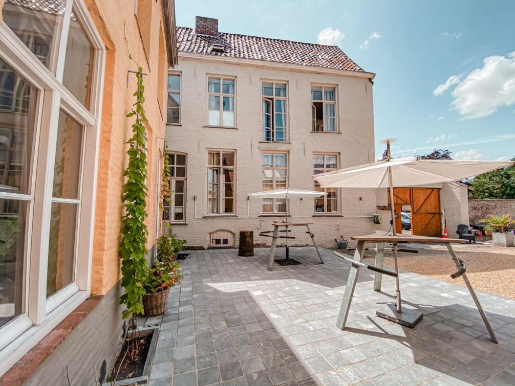 um pátio com uma mesa e um guarda-chuva em frente a um edifício em Skindles Guesthouse em Poperinge