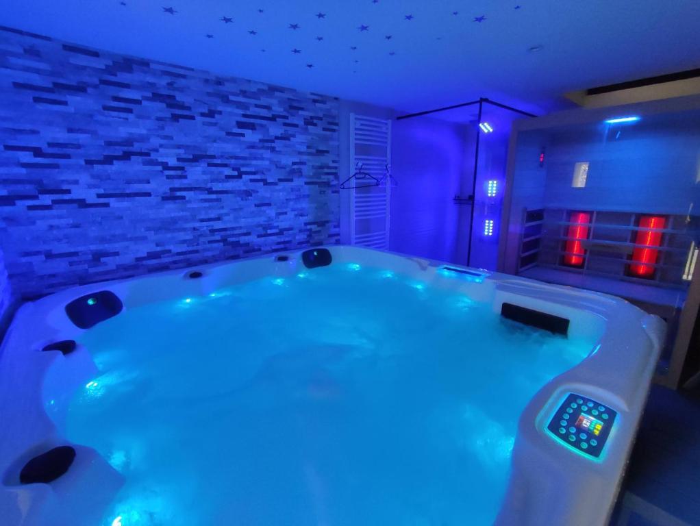 a bathroom with a large tub with blue lighting at Gîte Ange ou Démon, love room, jacuzzi, sauna, spa in Benfeld