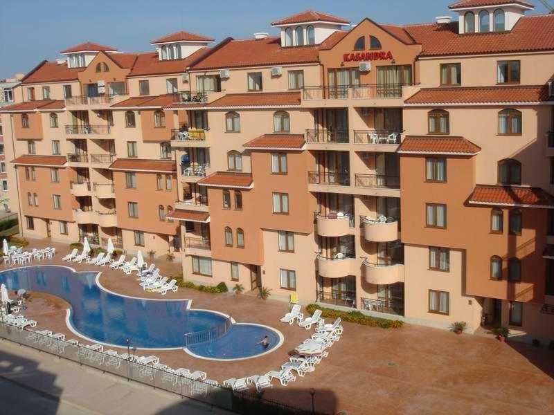a large apartment building with a swimming pool and chairs at Apart Hotel Kasandra in Sunny Beach