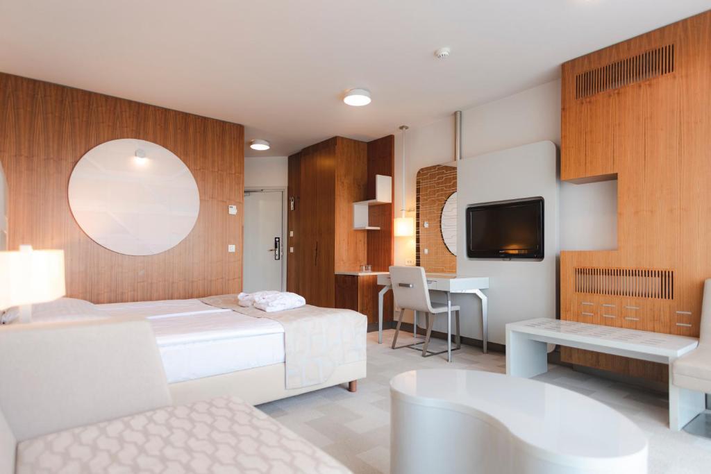 Schlafzimmer mit einem Bett, einem Schreibtisch und einem TV in der Unterkunft Hotel Terme - Terme Čatež in Čatež ob Savi