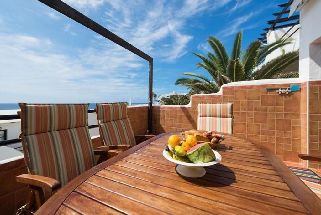 a plate of fruit on a wooden table on a balcony at Vista Faro Sardina in Las Palmas de Gran Canaria