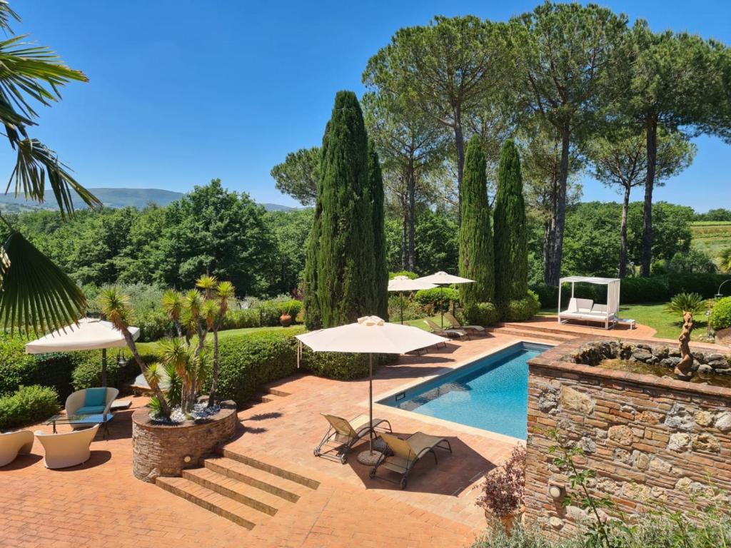 a garden with a swimming pool with umbrellas at Ripabella in San Gimignano