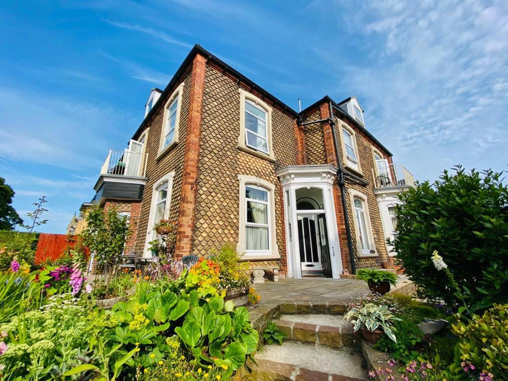 a large brick house with a garden in front of it at Fishtail House - Stylish Apartments minutes from the sea in Hornsea