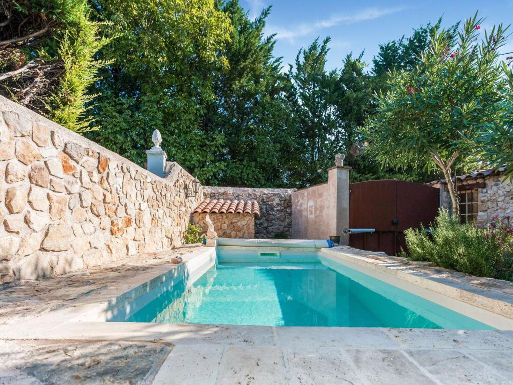 a swimming pool in a backyard with a stone wall at Charming holiday home in Lorgues with pool in Lorgues