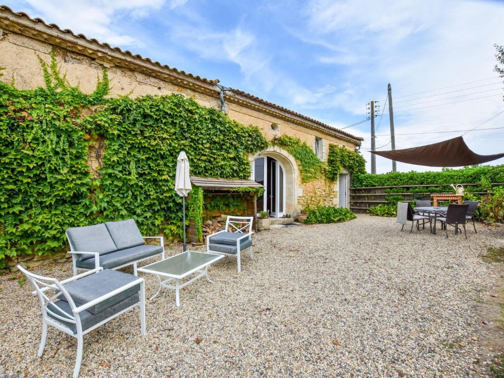 eine Terrasse mit Stühlen und Tischen vor einem Gebäude in der Unterkunft Stone house in a vineyard, with swimming pool, near Bordeaux in Monprimblanc