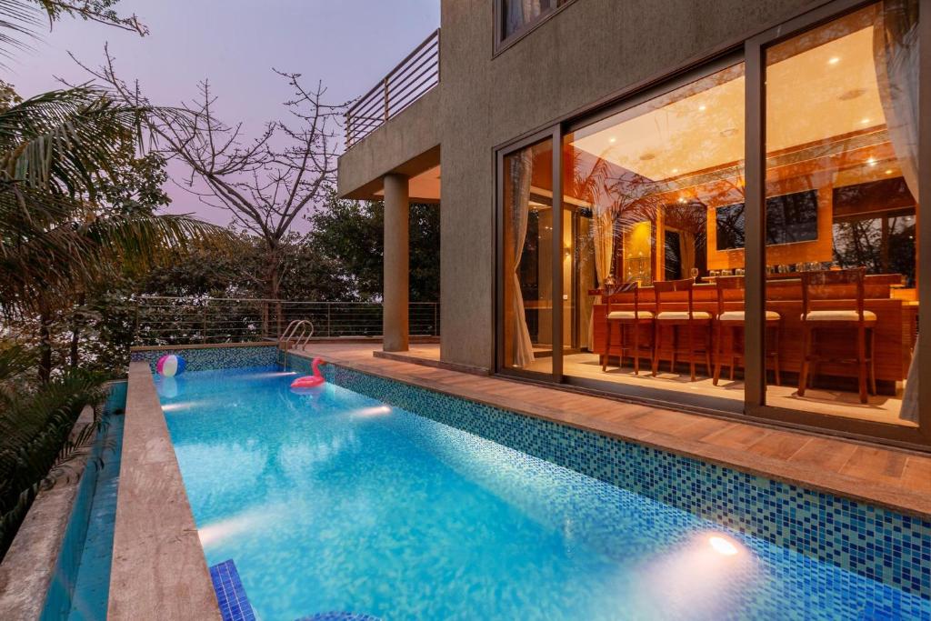 a swimming pool in front of a house at The Blue Horizon by StayVista - Featuring a beach-view villa with a swimming pool, indoor games, and a relaxing balcony in Alibaug