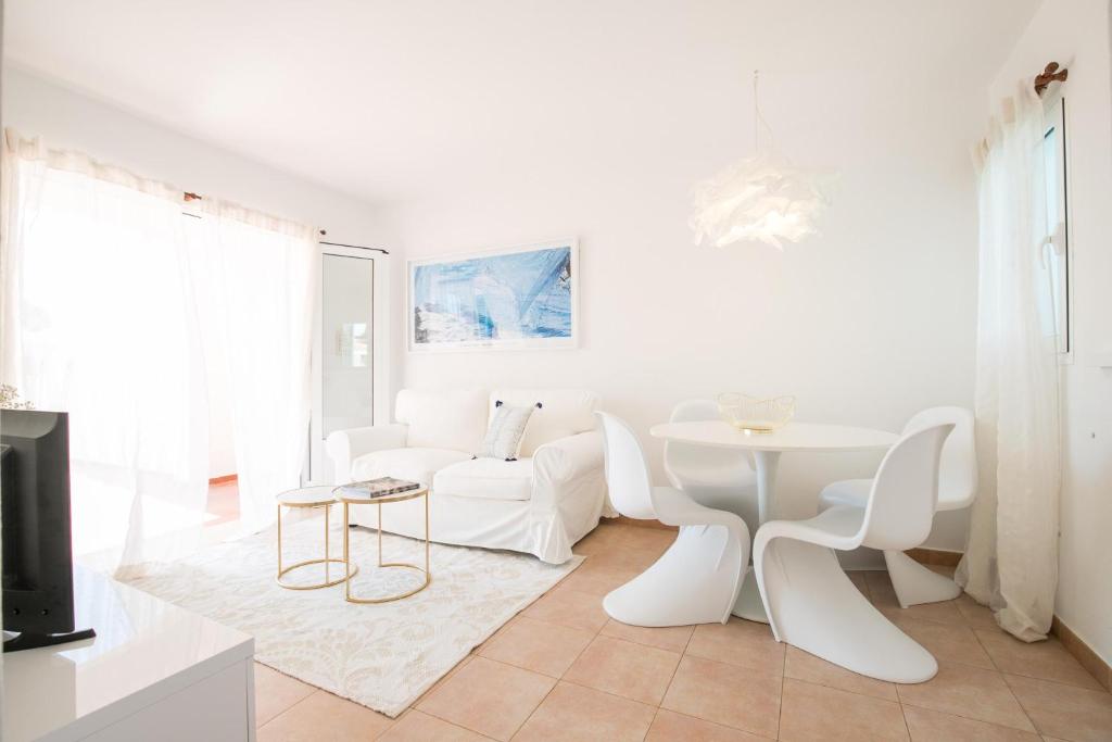 una sala de estar blanca con mesa blanca y sillas en Apartamentos Annabel's 2-3 HABITACIONES, en Cala Galdana