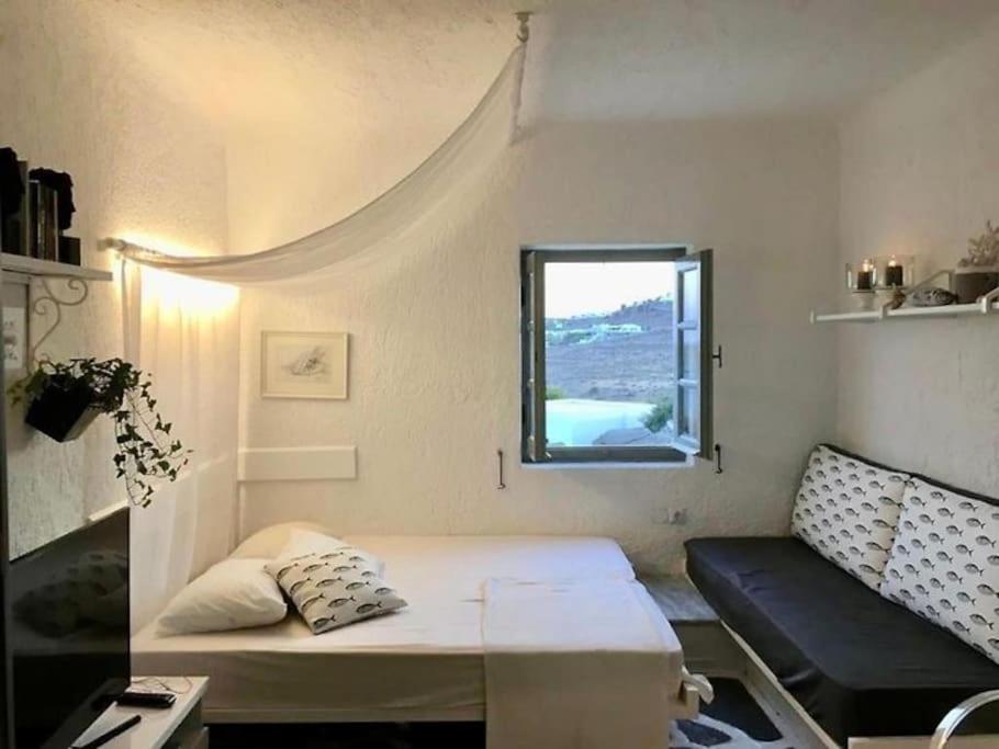 um pequeno quarto com uma cama e uma janela em Opis studio em Ornos