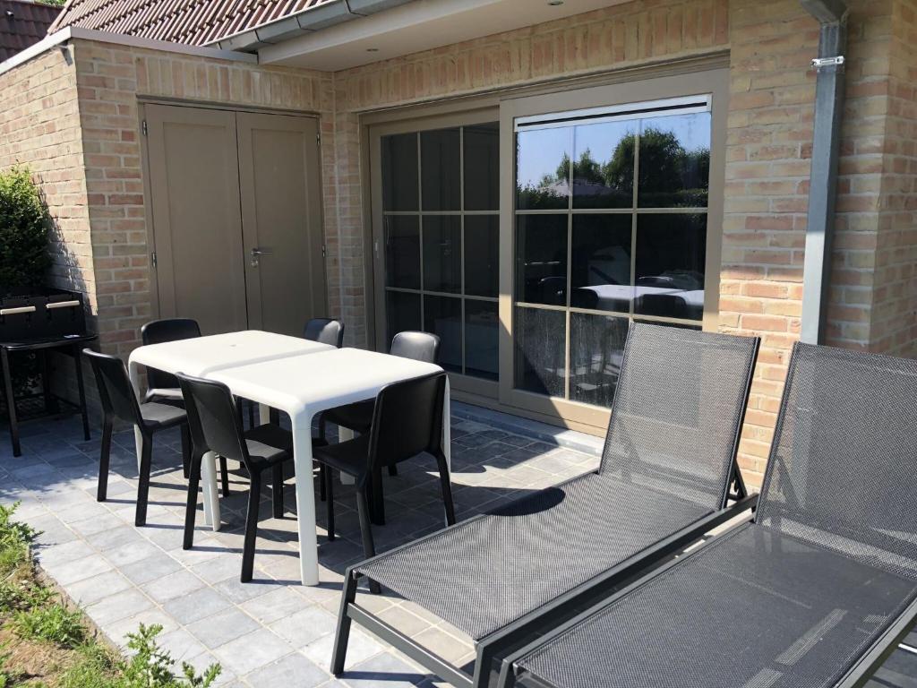 un patio con una mesa blanca y sillas en Cosy Holiday Home near Westhoek, en De Panne
