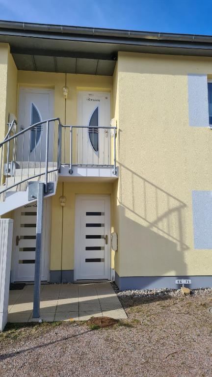 a yellow building with two doors and a balcony at Bernstein in Gelbensande
