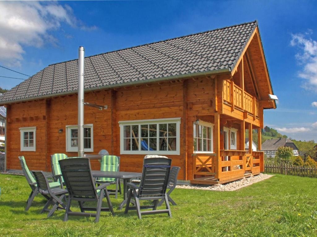 una baita di tronchi con un tavolo e sedie di fronte ad essa di Charming holiday home near the Sauerland ski area a Medebach
