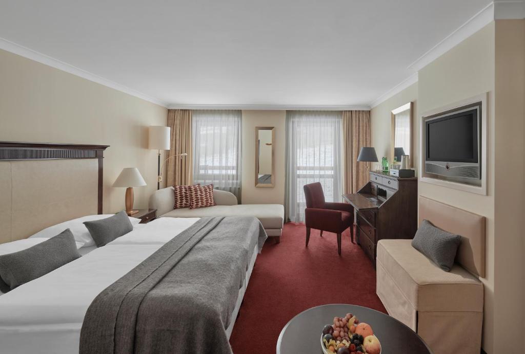 a hotel room with a large bed and a living room at Lebenberg Schlosshotel-Kitzbühel in Kitzbühel