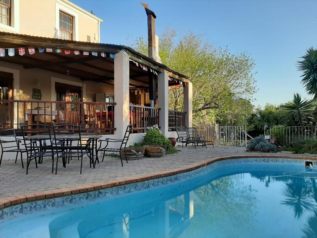 eine Terrasse mit einem Tisch und Stühlen neben einem Pool in der Unterkunft Karoo Life B&B in Calitzdorp