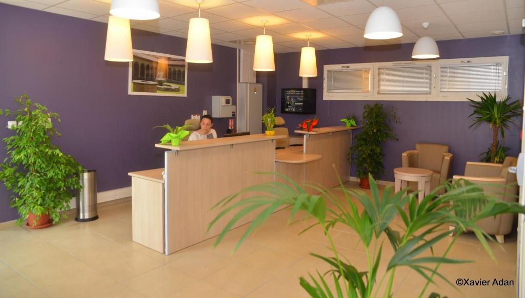 a woman sitting at a counter in an office with plants at Douce France in Cuxac-dʼAude