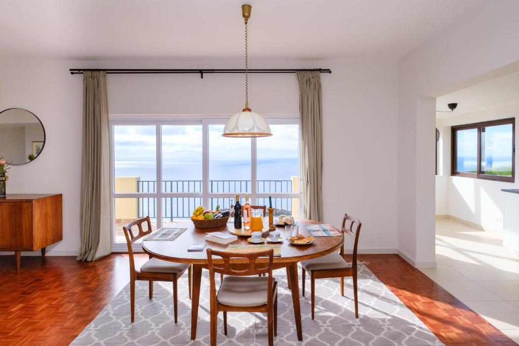 una cucina e una sala da pranzo con tavolo e sedie di Garajau House - Sunrise to Sunset Ocean View Villa a Caniço