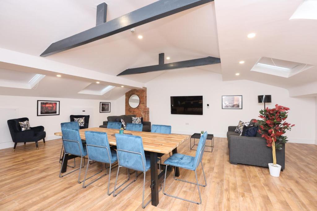 a dining room with a wooden table and blue chairs at Concert Square Apartments By Happy Days in Liverpool
