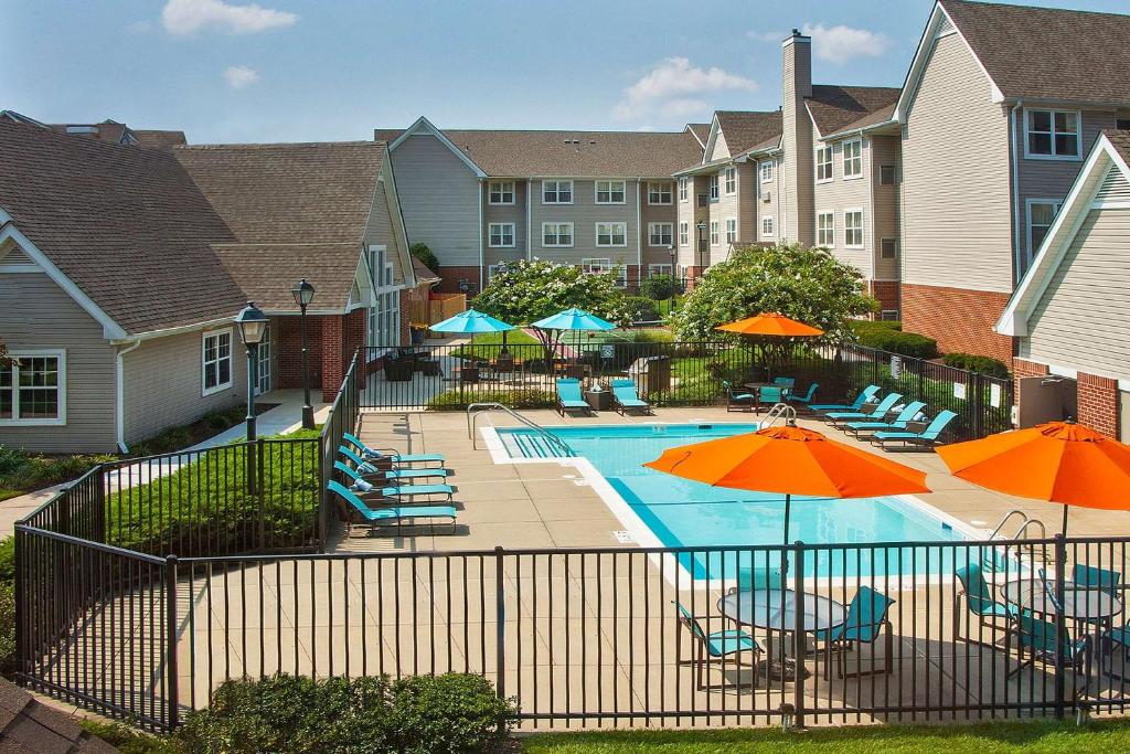 a pool with chairs and umbrellas in front of a building at Sonesta ES Suites Baltimore BWI Airport in Linthicum Heights