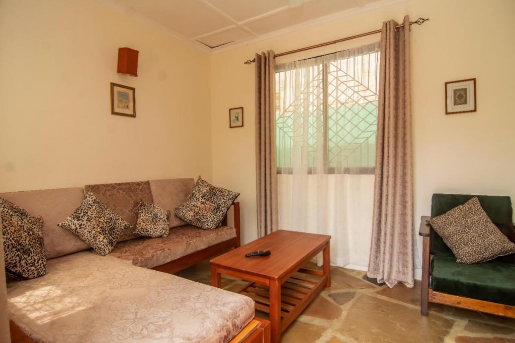 ein Wohnzimmer mit einem Sofa, einem Tisch und einem Fenster in der Unterkunft Amarrosi Buffalo-One Bedroom apartment, Mtwapa in Mtwapa