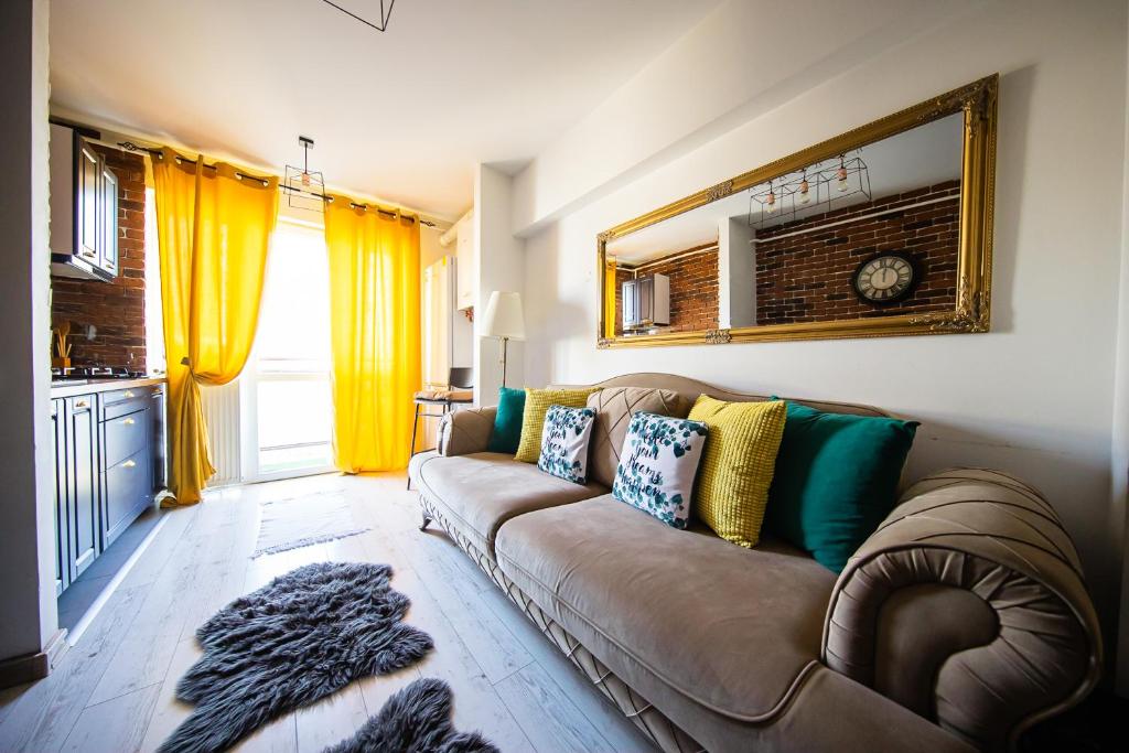 sala de estar con sofá marrón y cortinas amarillas en Smart Palas Apartament, en Iaşi