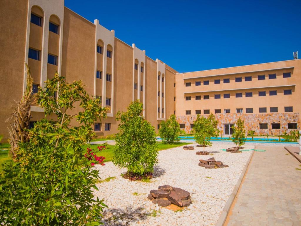 a building with a courtyard with trees in front of it at Hotel Monotel Dar El Barka in Nouakchott