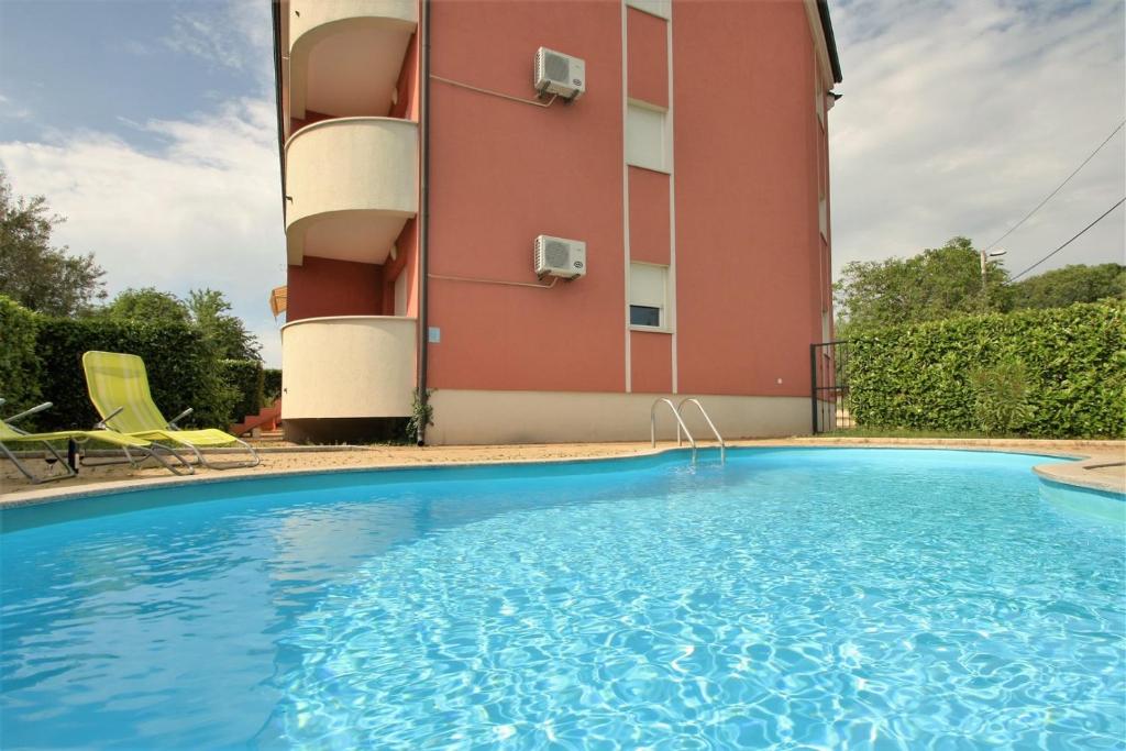 a building with a swimming pool in front of a building at Apartment Percic with Shared Pool in Vabriga