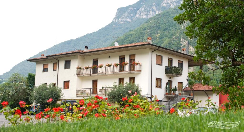 a white house with flowers in front of a mountain at Affittacamere La Martina in Vigano San Martino