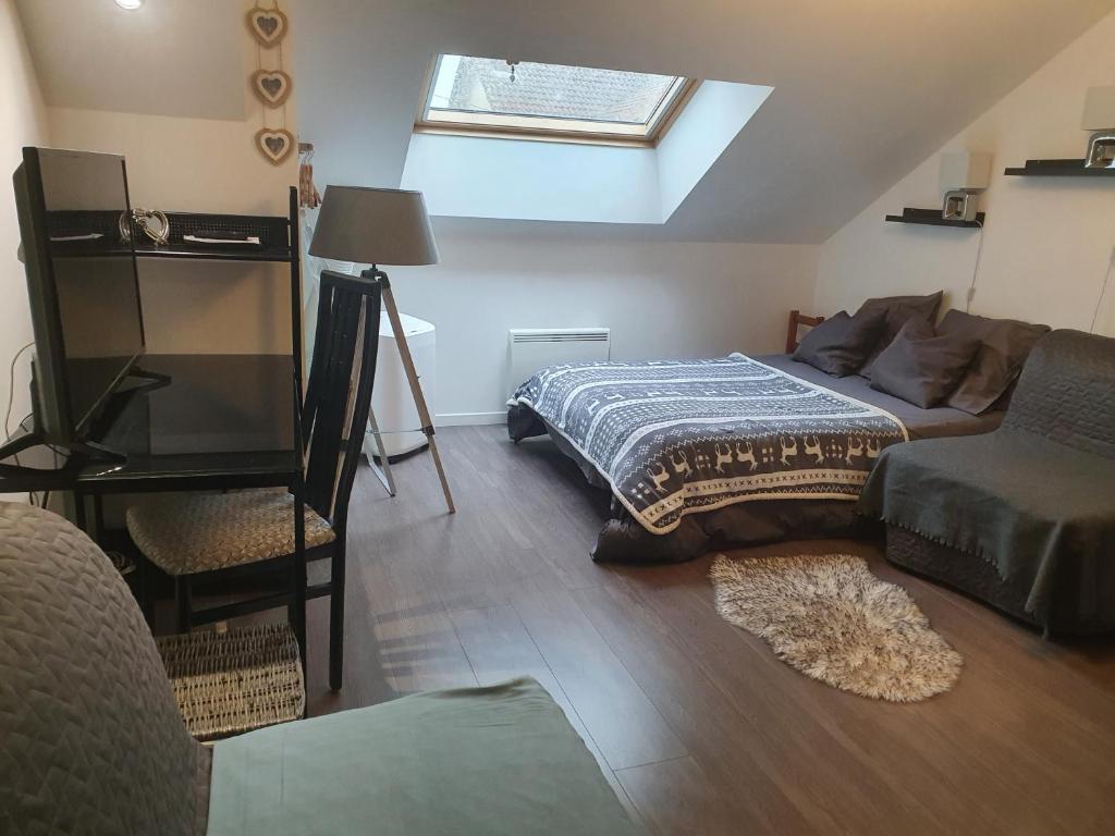 a bedroom with a bed and a couch and a window at Charles in Thaon-les-Vosges