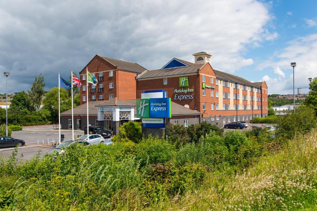 Holiday Inn Express Newcastle Gateshead, an IHG Hotel في نيوكاسل أبون تاين: مبنى من الطوب كبير مع موقف للسيارات أمامه