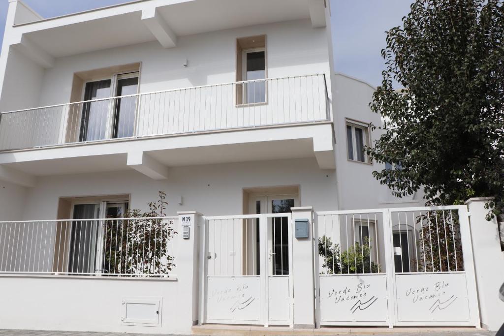 una casa bianca con cancelli bianchi e una recinzione di Verde Blu Vacanze Suites a Porto Cesareo