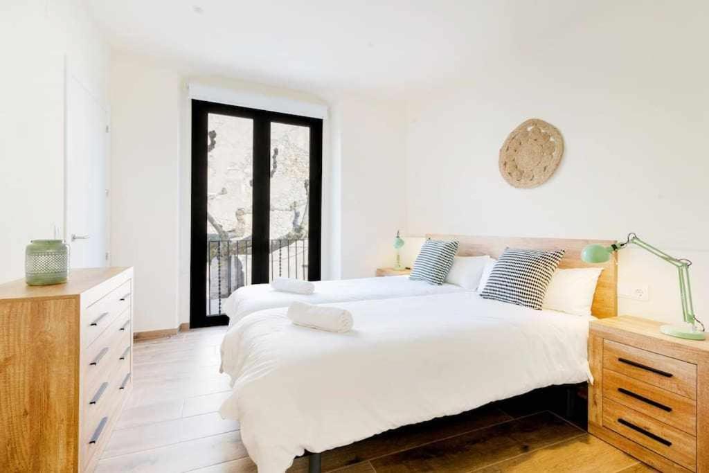 1 dormitorio blanco con 2 camas y ventana en Besalú 11 Moderno apartamento con AC en la plaza, en Besalú