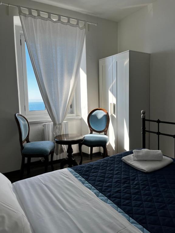 a bedroom with a bed and two chairs and a window at Villa Tergeste in Trieste
