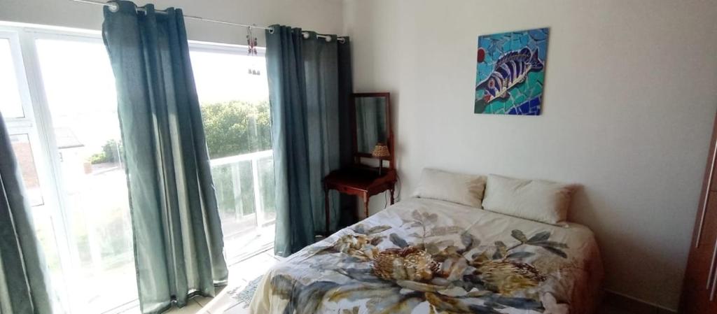 a bedroom with a bed and a large window at sandpiper in Jeffreys Bay