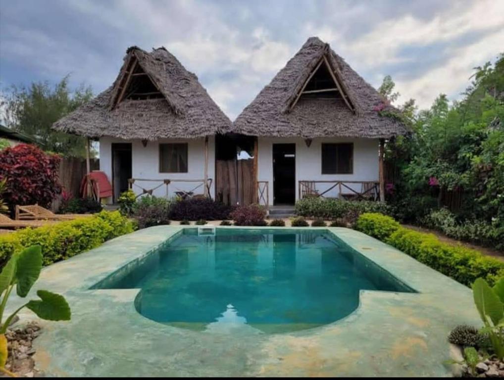 uma casa com uma piscina em frente em Sweet Home em Kiwengwa