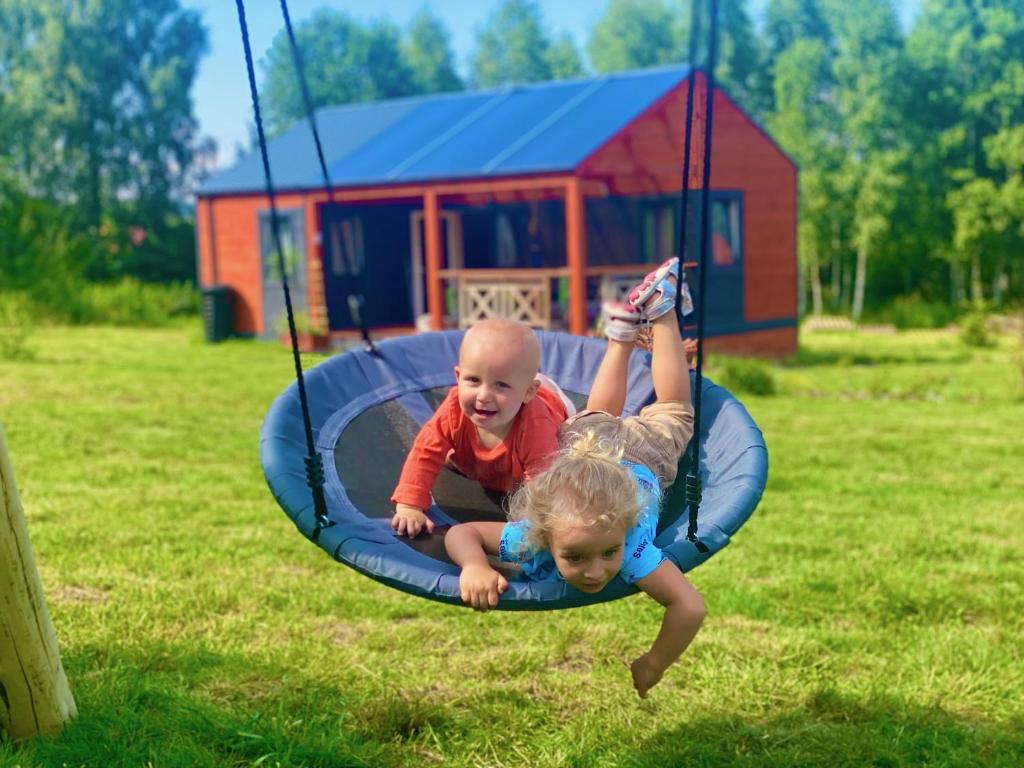 zwei Kinder spielen auf einem Trampolin im Hof in der Unterkunft Lazy Deer - Camp in Staniszów
