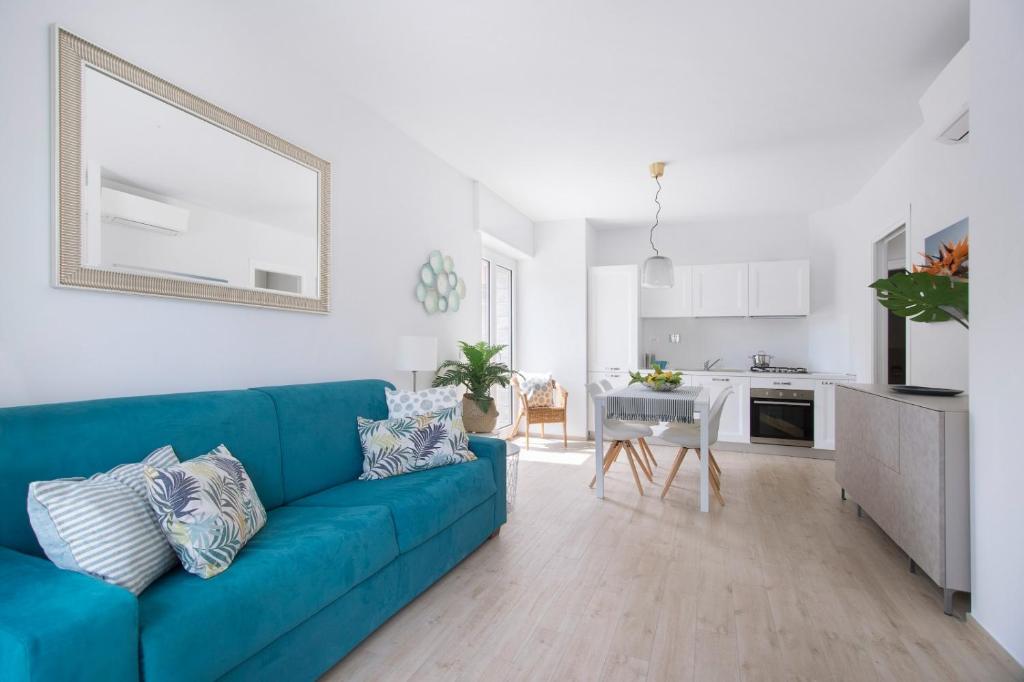 a living room with a blue couch and a kitchen at Italianway - Cristoforo Colombo 12 in San Bartolomeo al Mare