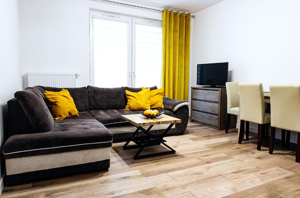 sala de estar con sofá y mesa con almohadas amarillas en Apartament Boryna, en Łomża